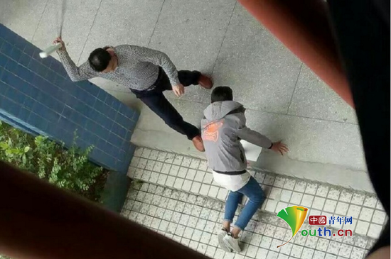 张姓老师手拿带插线板的电线殴打跪在地上的学生。